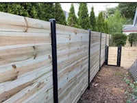 a wooden fence in a backyard with black railings