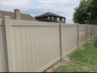 a beige vinyl fence in a backyard